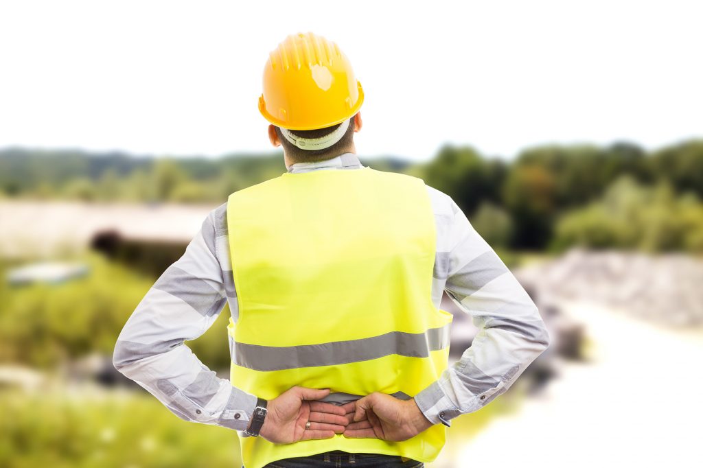 spinal cord injury - Injured construction worker or engineer suffering backpain in lower back area outdoor at work Birmingham